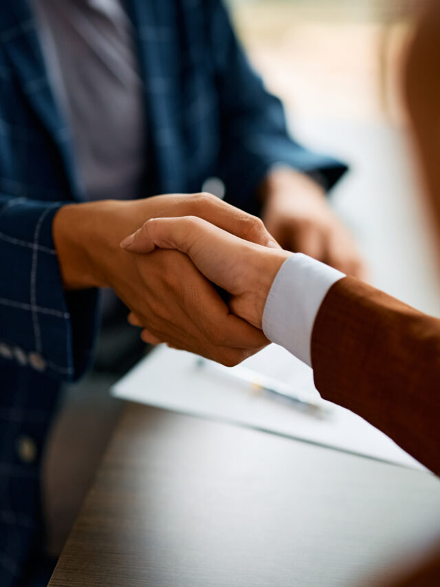 Close up of business people shaking hands in the office.