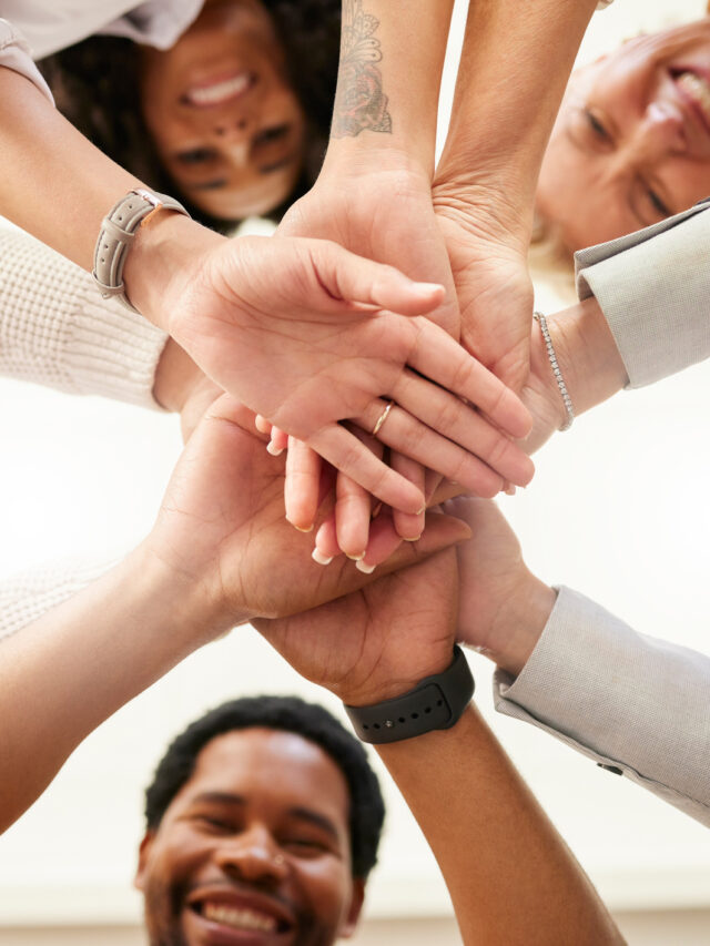 Office, team building and hands together from below in huddle for teamwork, collaboration and motivation at startup. Work, goals and diversity, group of people with business growth and staff support.