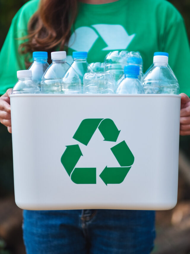 A woman collecting garbage and holding a recycle bin with plastic bottles